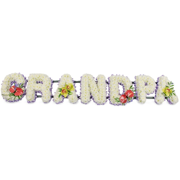 A striking funeral tribute forms the word "GRANDPA" in large, block capitals arranged in a single, long row against a clean white background, making every letter crisp and easy to read. Each character is lovingly covered with compact white chrysanthemums, their small, star-shaped petals tightly massed to create a dense, velvety surface that feels both luxurious and serene. Around the lower edge of each letter, a soft lavender ribbon subtly frames the blooms, its cool, pastel tone echoing the quiet mood of remembrance while helping each letter stand out clearly in the composition. The letters are discreetly joined by slim dark green supports, barely visible but essential for keeping the tribute aligned and stable when placed beside a coffin or on a stand at a church or crematorium near Lisson Grove or Baker Street. Splashes of vivid colour have been thoughtfully introduced to tell a more personal story. The leftmost 'G' and the central 'D' carry compact sprays of deep red anthuriums, their waxy, heart-shaped petals and bright yellow spadices nestled among rich green foliage and tiny, delicate purple filler flowers, bringing passion and warmth to the tribute. The first 'A' and the final 'A' on the right are highlighted with graceful yellow-green orchid clusters, their slender petals, subtle spots, and elegant curves adding a refined, contemporary note to the otherwise traditional white arrangement. Crafted with the care of a local florist who understands the sensitivities of farewell, this "GRANDPA" design feels perfectly suited to families in Lisson Grove seeking a tribute that balances classic white funeral flowers with distinctive accents. It offers a gentle yet unmistakable way to honour a grandfather's life, presence, and lasting influence within the family.